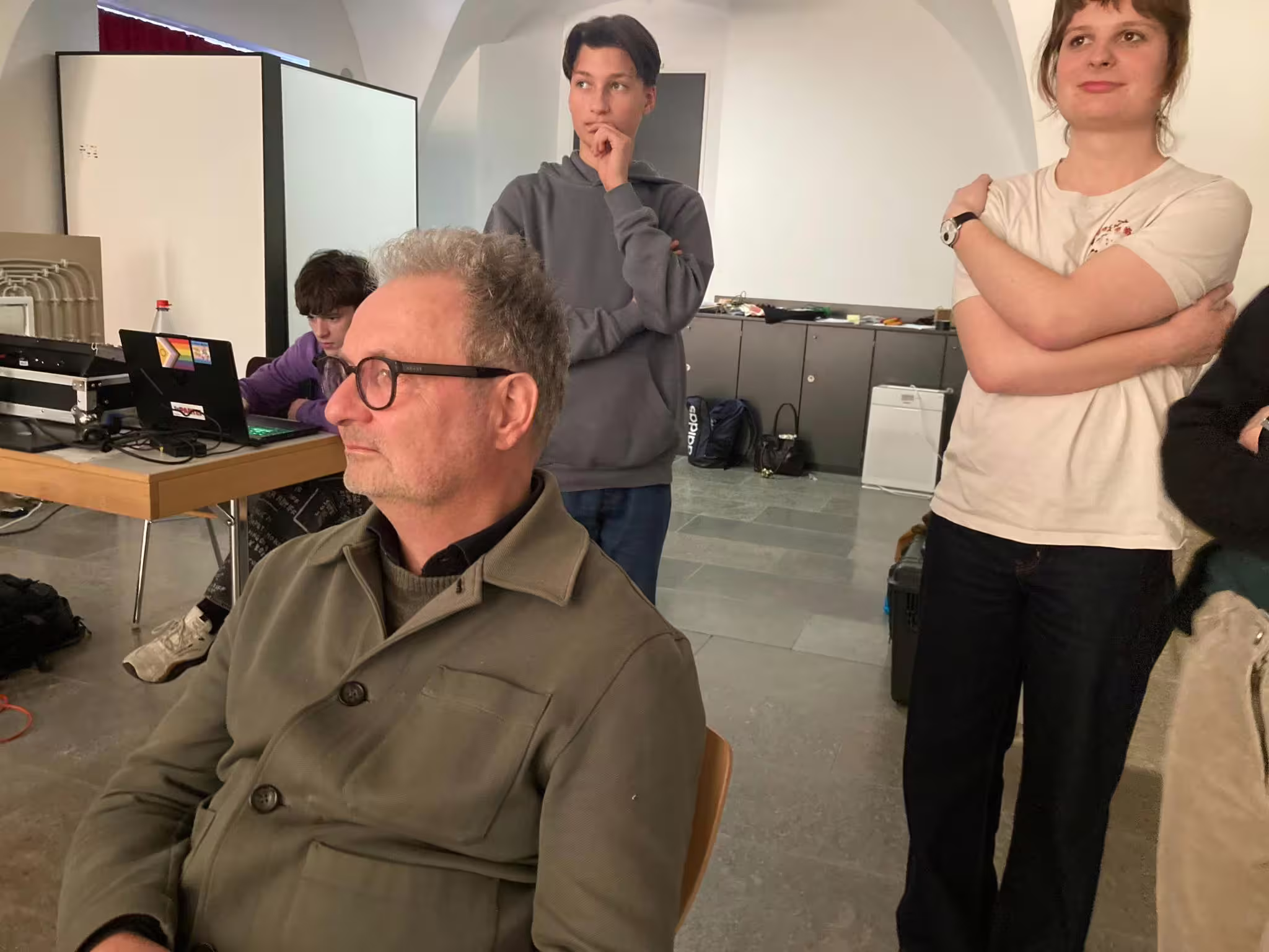 Älterer Mann mit Brille sitzt vorn, dahinter Jugendliche am Laptop und stehend in Hoodie und T‑Shirt bei AUFBLENDE2026